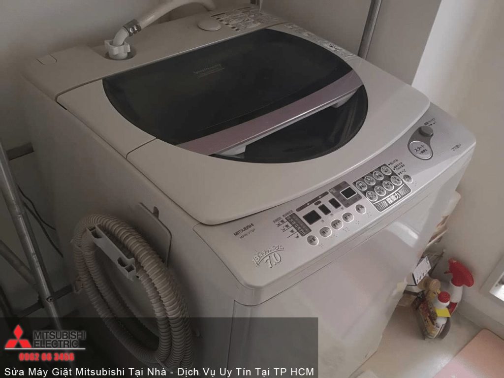 Washing machine in a laundry room with control panel and flexible hose.