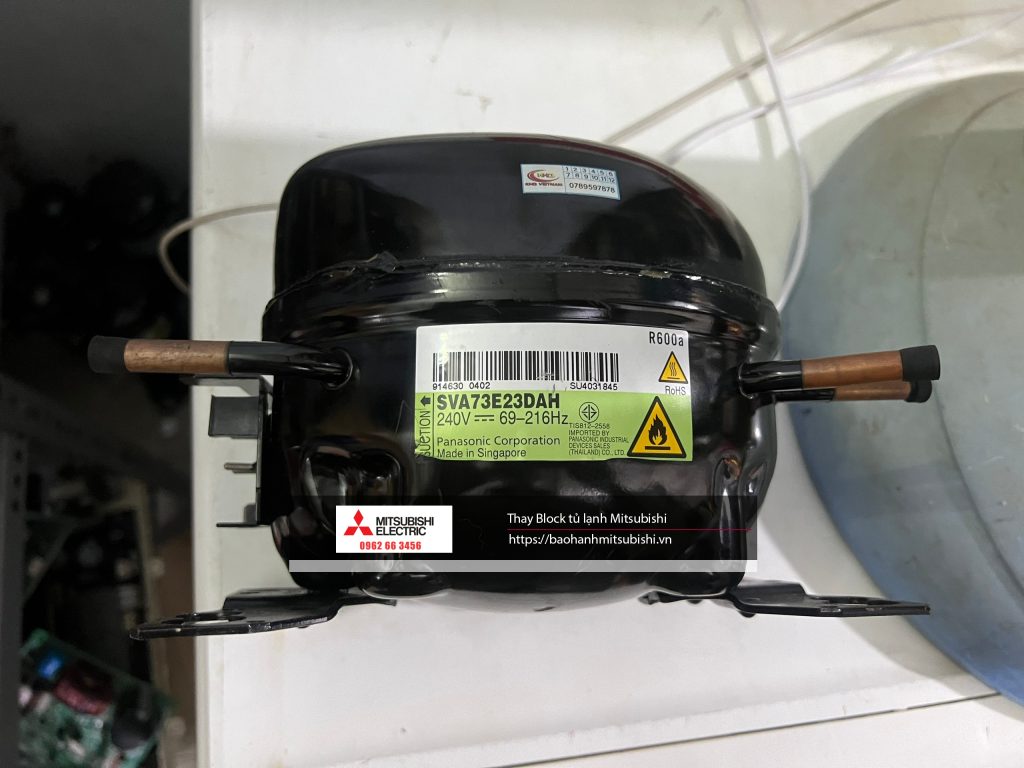 High-quality Mitsubishi electric refrigerator compressor with safety and voltage labels, used for vehicle cooling systems, compatible with Mitsubishi models, manufactured in Singapore for optimal performance.